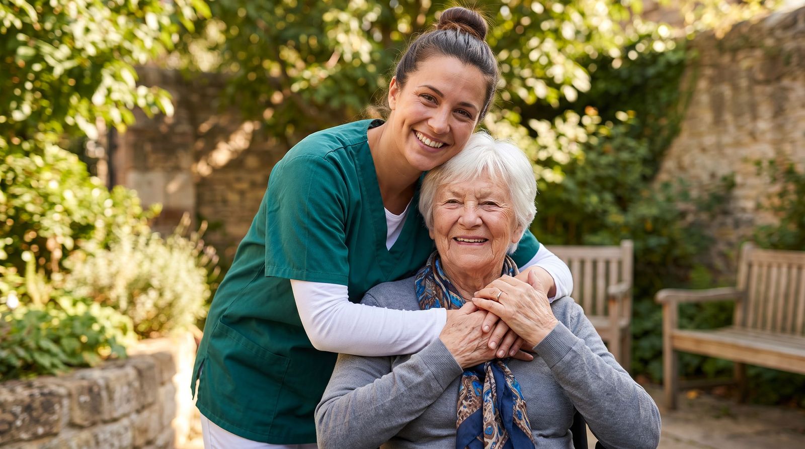 A support worker hugging an older woman in a sunny garden